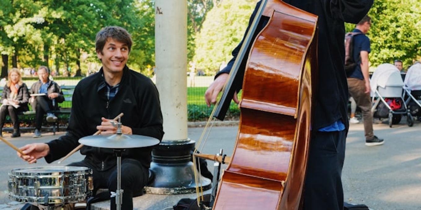 Street musicians with a double bass and drums in a park setting.