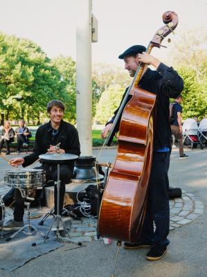 Street musicians with a double bass and drums in a park setting.